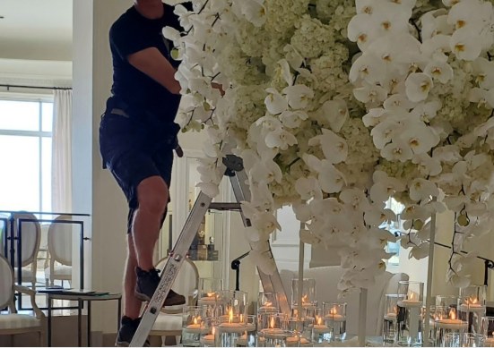 Fleuriste installant une grande composition d'orchidées pour un événement